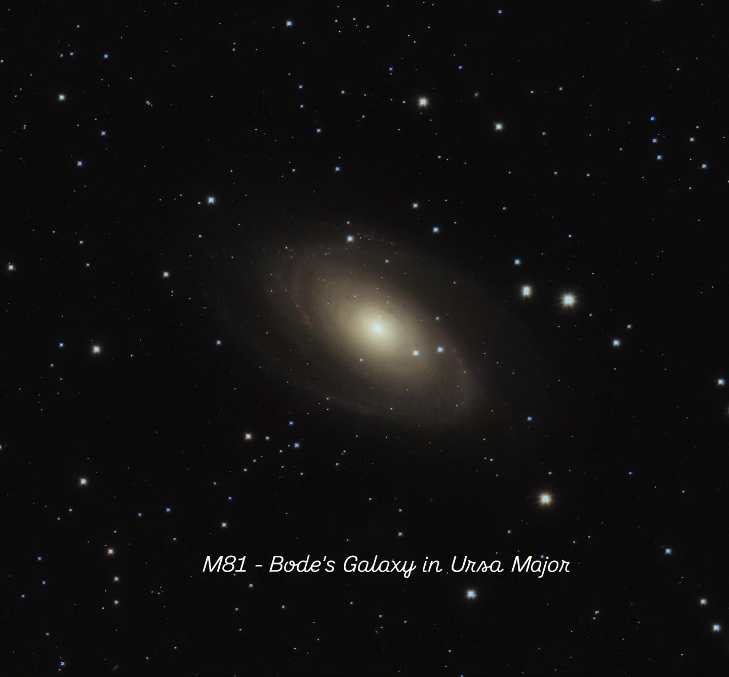 Oval spiral galaxy with a bright yellowish core and faint arms among scattered stars