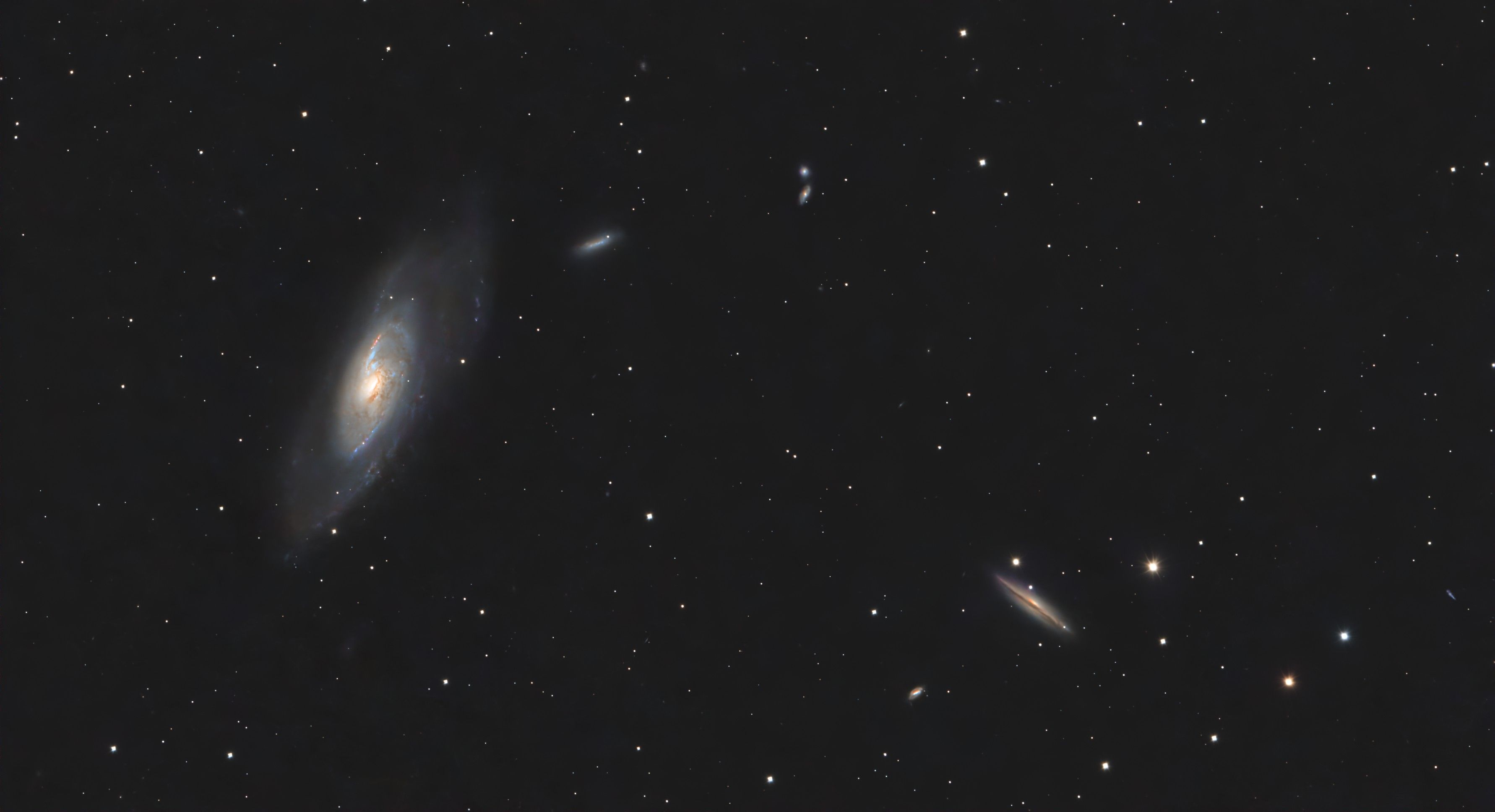 Large tilted spiral galaxy with a bright core, with a smaller companion galaxy at lower right, among scattered stars