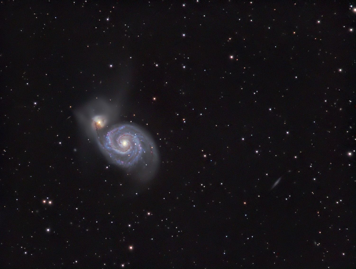 Face-on spiral galaxy linked to a smaller yellowish companion galaxy above it
