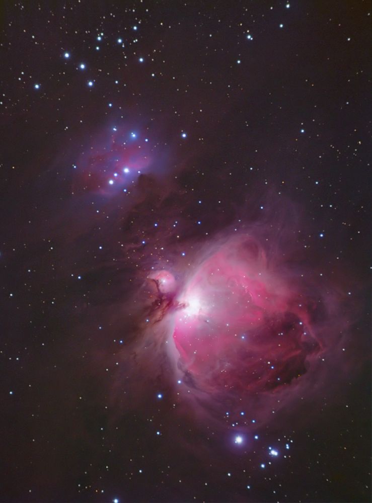 Vertical view of the pink Orion Nebula at bottom with the blue Running Man Nebula above it