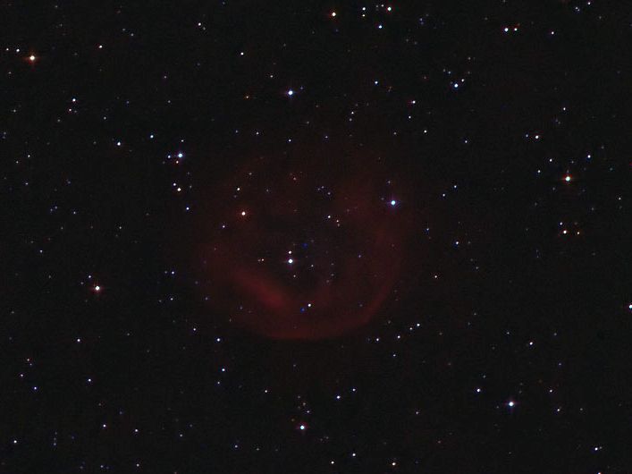 Faint roughly circular red shell of nebulosity near the centre of a star field