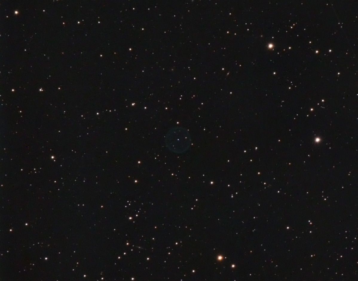 Dark star field with a very faint small blue-green ring near the centre