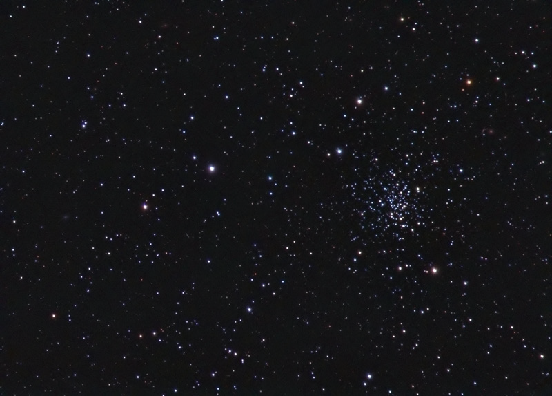 Compact open cluster of blue-white stars at lower right of a dense star field