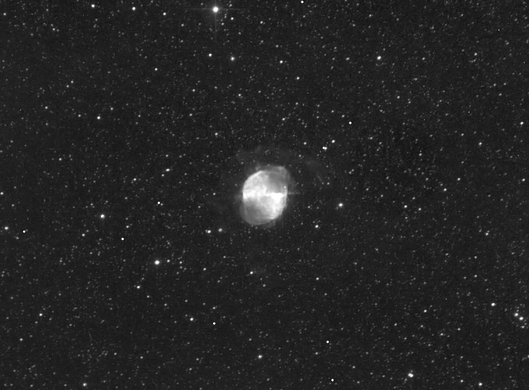 Black-and-white image of an apple-core-shaped glowing nebula in a dense star field