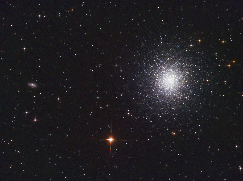 Bright globular cluster of thousands of stars with a small galaxy to the left