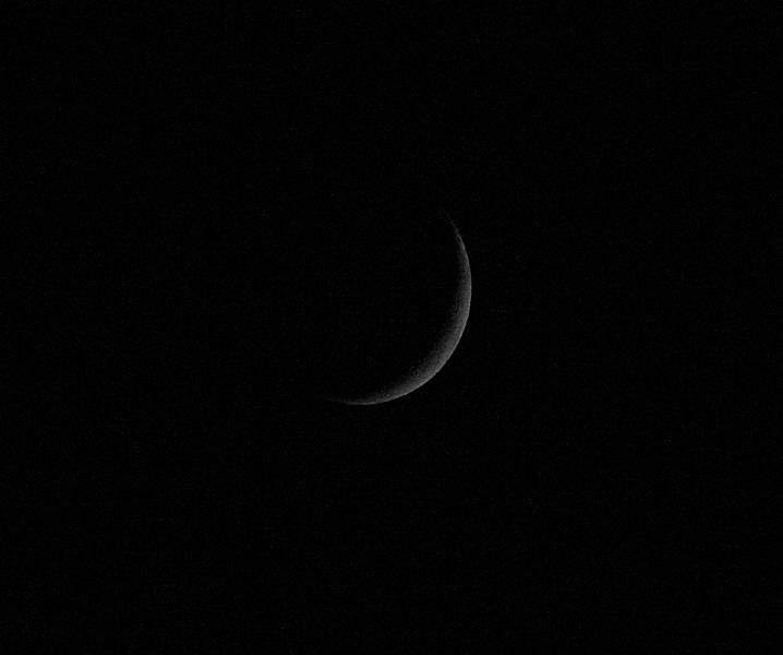 Thin crescent Moon lit on its right side against a black sky