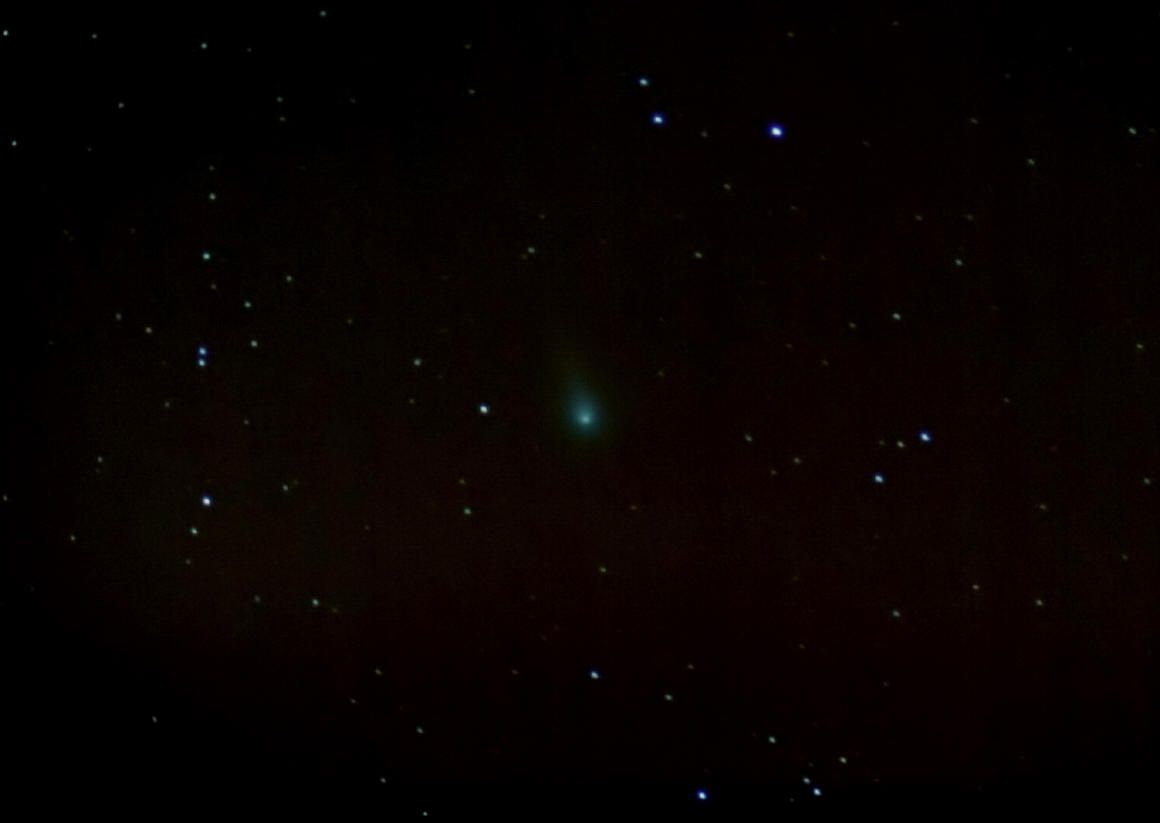 Small green comet coma among scattered stars