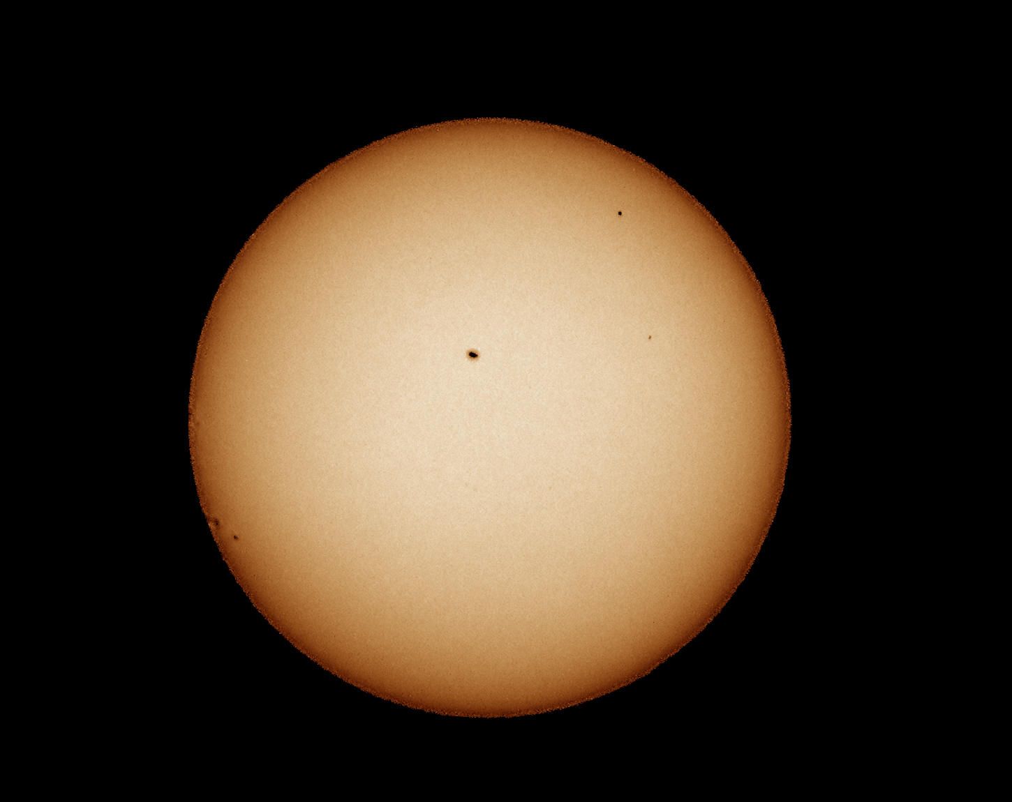 Yellow solar disc with a tiny black dot of Mercury and a few small sunspots