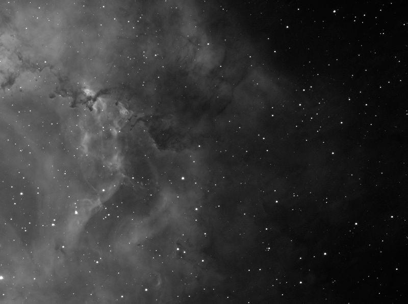 Black-and-white clouds of glowing gas with dark dust lanes filling the left side of the frame